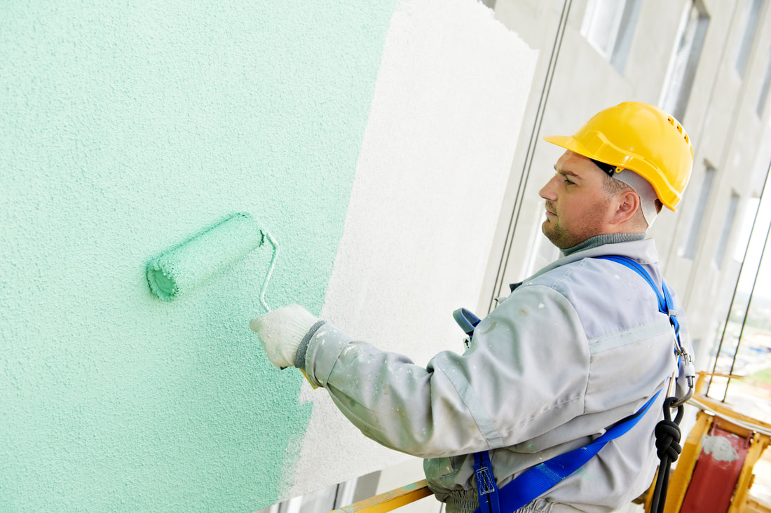 Worker applying paint to the wall in Fredericton New Brunswick